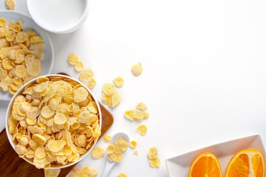 Corn flakes bowl sweeties with milk and orange on white background, top view, flat lay overhead layout, fresh and healthy breakfast design concept.