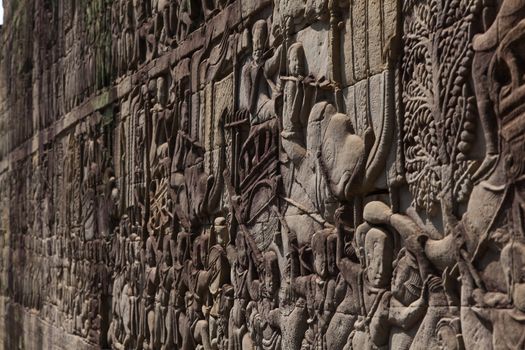 Angkor Watt, Cambodia is a temple complex with hundreds of temples decorated with sculptures, statues and wall reliefs. Many depict gods, kings and times of war. The are shot with side lighting giving texture and details to the subjects wall relief depicting ancient wars. High quality photo