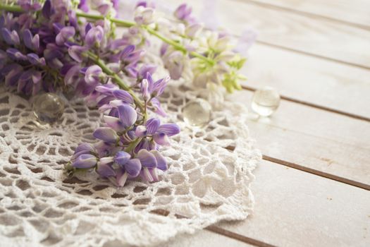 lovely lupine and vintage lace on rustic white wooden background in light, floral greeting card.