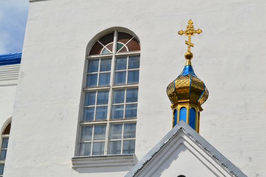 Golden dome of the Orthodox church in Belarus. Byzantine cross with window and white wall, Slonim, Belarus