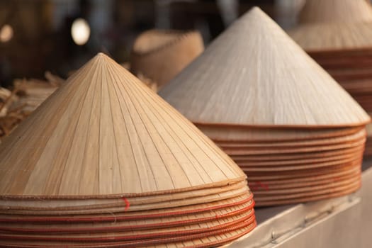 Traditional Vietnamese conical leaf hats, made from palm leaves. Called non la sometimes referred to as poem hats for sale in market, warm colours . High quality photo