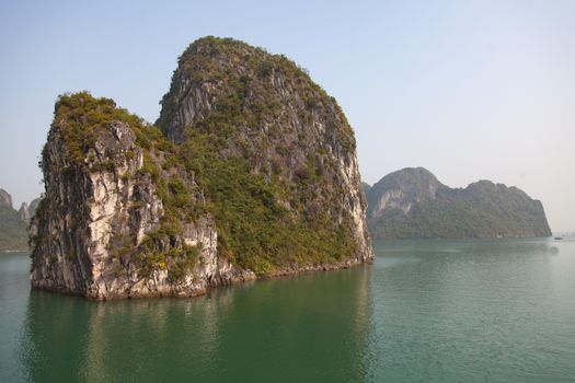 Ha Long Bay, Vietnam, is a World Heritage Site and very popular with tourists. Thousands of towering limestone islands topped by rainforests rising up out of the emerald seas. Cruise ships take tourists for day trips and overnight stays in the bay. , . High quality photo