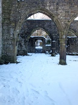 arches and columns in the ruined medieval church in hebden bridge west yorkshire with snow covering the ground in winter
