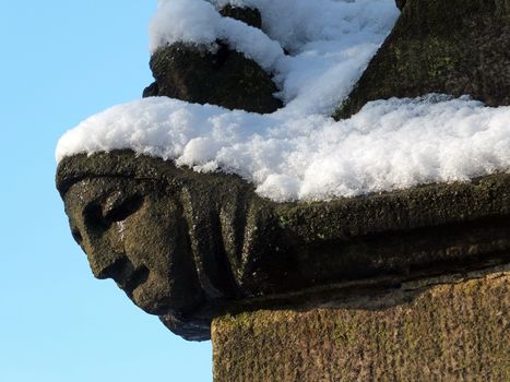 close up of the carving of a womans face in profile on the corner of the ancient ruined medieval church in heptonstall west yorkshire covered in winter snow