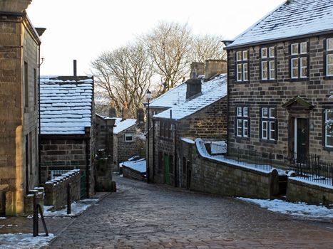 the historic yorkshire village of heptonstall in winter with snow covered roofs and street