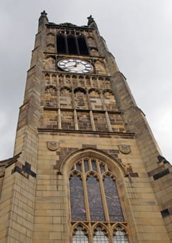 view of the clock tower and building of the historic saint peters parish church in the center of huddersfield against a cloudy sky