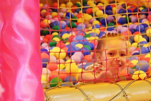 smiling girl in a dry pool with balls behind a net