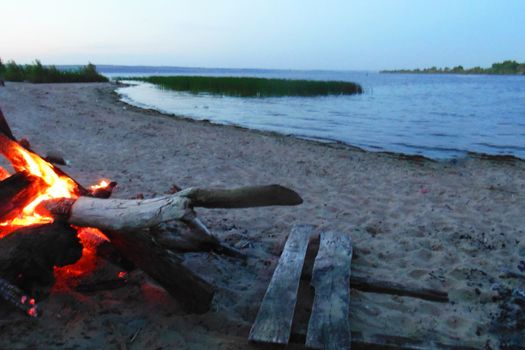 bonfire by the lake in the evening on the background of sunset