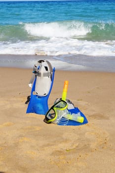 flippers and mask for swimming on the sand against the background of the sea and clear sky, copy space