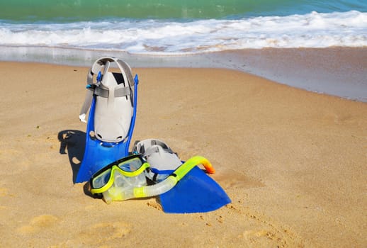 flippers and mask for swimming on the sand against the background of the sea and clear sky, copy space