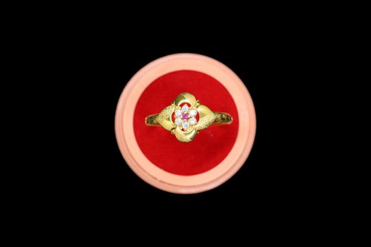 Beautiful gold ring and unique workmanship of white stones in it., Jewels with red gift box on black background