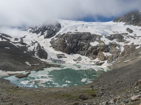 summer view of the Sulzenauferner Glacier and turquoise glacial lake and waterfall from melting ice. Stubai Alps, Austria.