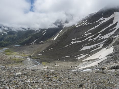 Summer view of alpine mountain valley with winding stream and glacial lake, Sulzenauferner Glacier, Stubai Alps, Austria.