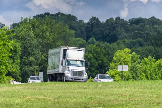 Traffic in Tennessee on a hot day.  Shimmering waves of heat from the pavement adds an interesting texture to the vehicles and trees behind them.