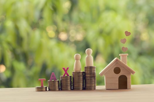 Small wooden house and heart, family members, words tax, on rows of rising coins on table. Family tax benefit, residential property tax concept: depicts home equity loan, real estate business investme
