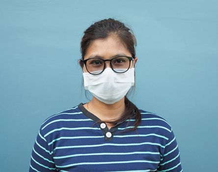 Portrait of Asian women wearing glasses and protective masks on a blue background.