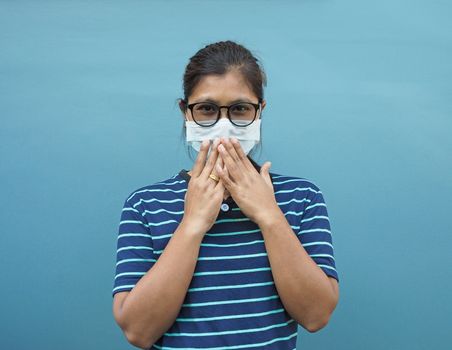 Portrait of Asian women wearing glasses and protective masks. While covering his mouth On a blue background