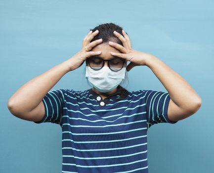 Portrait of Asian women wearing glasses and protective masks. While showing a headache On a blue background