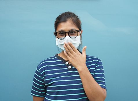 Portrait of Asian women wearing glasses and protective masks. While covering his mouth On a blue background