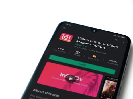 Lod, Israel - July 8, 2020: InShot - Video Editor & Movie Maker app play store page on the display of a black mobile smartphone isolated on white background. Top view flat lay with copy space.