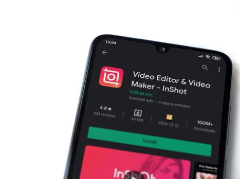 Lod, Israel - July 8, 2020: InShot - Video Editor & Movie Maker app play store page on the display of a black mobile smartphone isolated on white background. Top view flat lay with copy space.