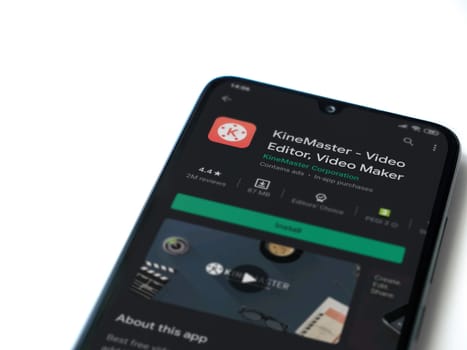 Lod, Israel - July 8, 2020: KineMaster - Video Editor & Movie Maker app play store page on the display of a black mobile smartphone isolated on white background. Top view flat lay with copy space.