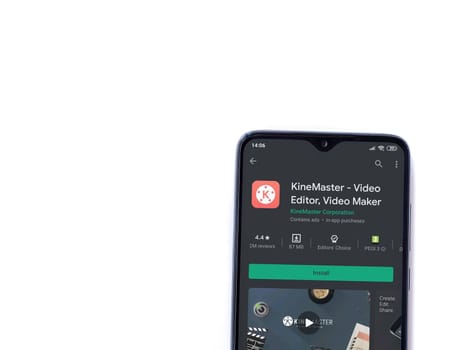 Lod, Israel - July 8, 2020: KineMaster - Video Editor & Movie Maker app play store page on the display of a black mobile smartphone isolated on white background. Top view flat lay with copy space.