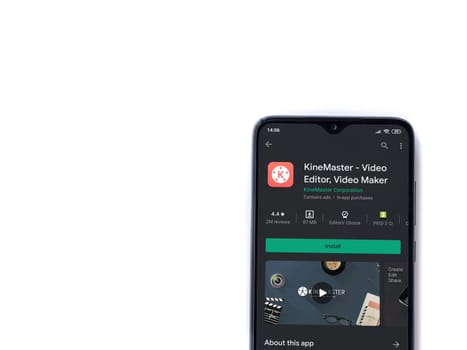 Lod, Israel - July 8, 2020: KineMaster - Video Editor & Movie Maker app play store page on the display of a black mobile smartphone isolated on white background. Top view flat lay with copy space.
