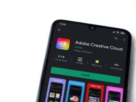 Lod, Israel - July 8, 2020: Adobe Creative Cloud app play store page on the display of a black mobile smartphone isolated on white background. Top view flat lay with copy space.
