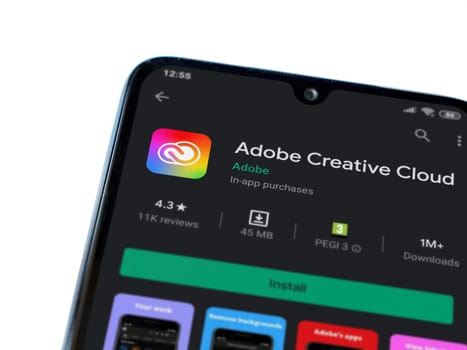 Lod, Israel - July 8, 2020: Adobe Creative Cloud app play store page on the display of a black mobile smartphone isolated on white background. Top view flat lay with copy space.