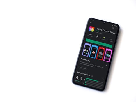 Lod, Israel - July 8, 2020: Adobe Creative Cloud app play store page on the display of a black mobile smartphone isolated on white background. Top view flat lay with copy space.