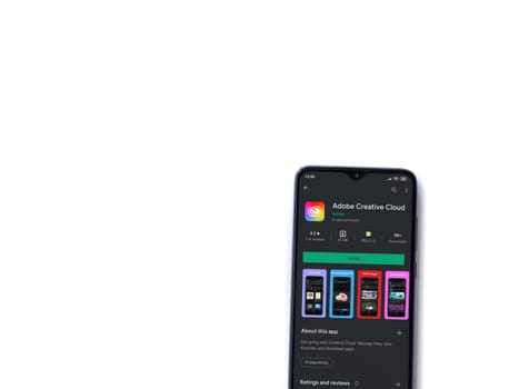 Lod, Israel - July 8, 2020: Adobe Creative Cloud app play store page on the display of a black mobile smartphone isolated on white background. Top view flat lay with copy space.