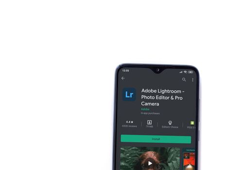 Lod, Israel - July 8, 2020: Adobe Lightroom - Photo Editor & Pro Camera app play store page on the display of a black mobile smartphone isolated on white background. Top view flat lay with copy space.