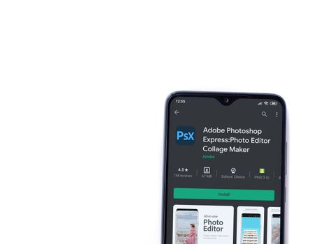 Lod, Israel - July 8, 2020: Adobe Photoshop Express Photo Editor app play store page on the display of a black mobile smartphone isolated on white background. Top view flat lay with copy space.