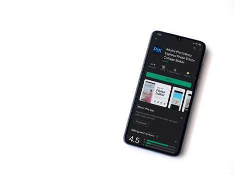 Lod, Israel - July 8, 2020: Adobe Photoshop Express Photo Editor app play store page on the display of a black mobile smartphone isolated on white background. Top view flat lay with copy space.