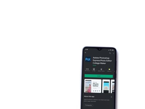 Lod, Israel - July 8, 2020: Adobe Photoshop Express Photo Editor app play store page on the display of a black mobile smartphone isolated on white background. Top view flat lay with copy space.