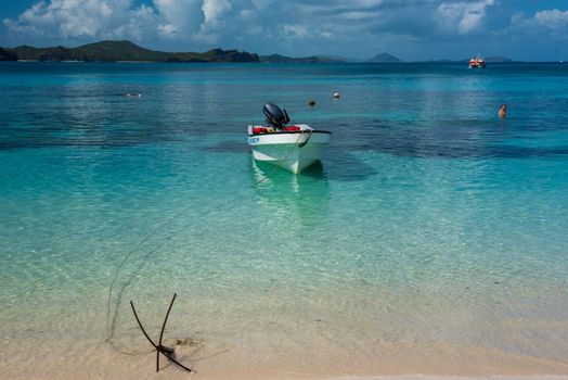 Fiji, South Pacific -- February 7, 2016. A boat is anchored close to shore at a Fijian beach; tourists are in the water and a tender boat heads toward