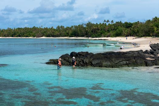 Fiji, South Pacific -- February 7, 2016. Tourists wade into the pristine waters of Fiji on a summer day.