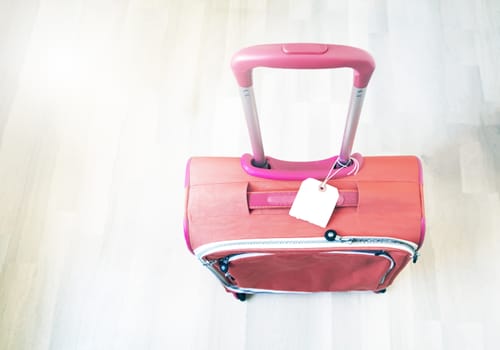 top view of a red suitcase with the handle raised and a blank label. Travel and tourism concept.