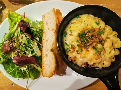 Macaroni cheese with baguette bread and organic salad