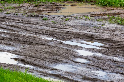 dirty clay mud road with puddles and tire tracks - closeup with selective focus and blur, diagonal composition