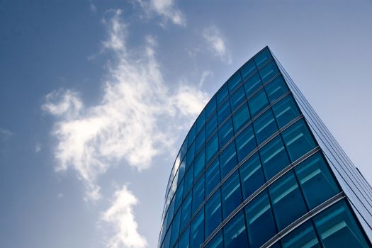 Part of modern glass and steel building forming lines against deep blue skies