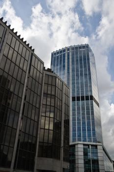 Modern blue and grey office buildings in London banks district with sky and clouds in background