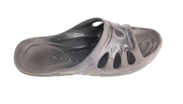 one used cheap black soft rubber slipper with signs of friction wear isolated on white background.