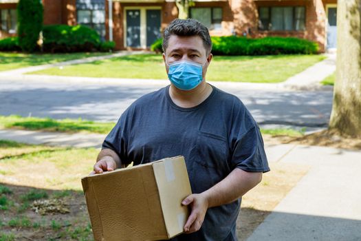 Home delivery, online order a man in a medical mask with a box, a parcel in his hands food delivery during the quarantine of the coronavirus pandemic.
