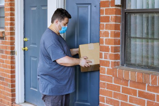Online order home delivery, man medical mask with hard working delivery man holding a box parcel of the coronavirus pandemic