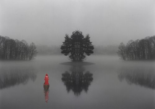 Figure in red cloak floats in boat in mystic forest lake