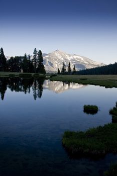 Calm water, trees and mountains at the horizon