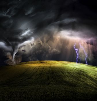 Tornado in stormy landscape. Lightnings and sunbeams over green field