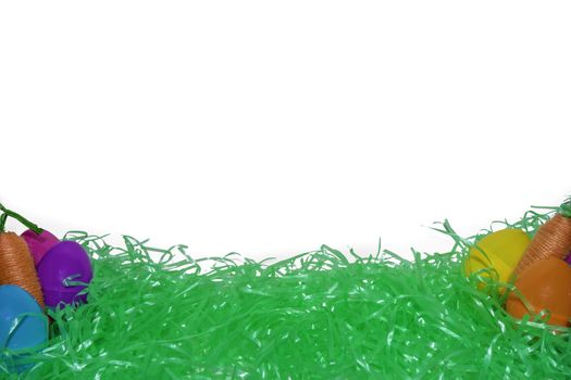 Green Easter Grass, Colorful Eggs, and Carrots With a Pure White Background Behind It